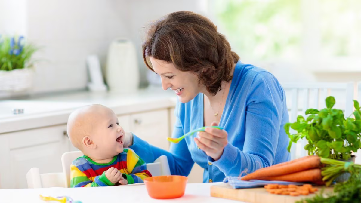 Mother feeding baby with baby puree and starting solids.